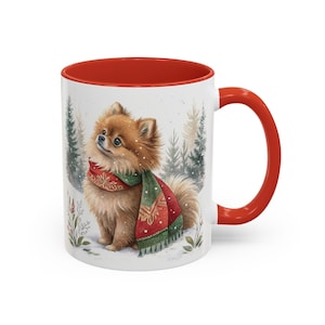May include: A white ceramic mug with a bright red interior and handle. The exterior features a detailed illustration of a fluffy brown Pomeranian dog wearing a red and green patterned scarf, set against a snowy winter forest background.