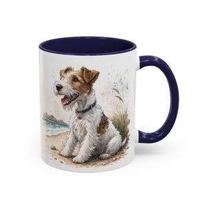 May include: White ceramic mug with a navy blue interior and handle. The mug features a watercolor illustration of a terrier dog sitting on a beach. The dog has brown and white fur and is wearing a blue collar. The background shows a beach scene.