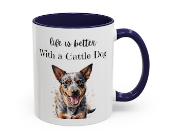 May include: A white ceramic mug with a dark blue interior and handle. The front features a watercolour-style illustration of a blue heeler dog and the black text "life is better With a Cattle Dog" printed in a mix of script and serif fonts.