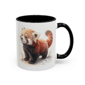 May include: White ceramic mug with a black interior and handle. The mug features a watercolor illustration of a red panda. The red panda has reddish-brown fur and is standing on a light-colored surface.