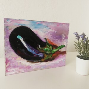 May include: An oil painting of a large, dark purple eggplant with a green stem and leaves. The background is a blend of pink, purple, and blue brushstrokes, creating a textured effect. The artwork is displayed on a white surface.