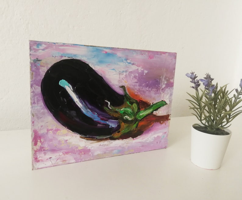 May include: An oil painting of a large, dark purple eggplant with a green stem and leaves. The background is a blend of pink, purple, and blue brushstrokes, creating a textured effect. The artwork is displayed on a white surface.