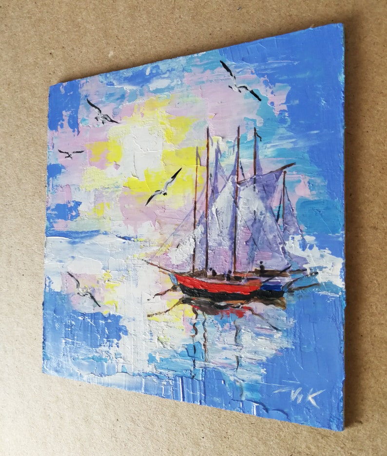 May include: A painting of a sailboat with white sails on a blue and pink water background with a yellow sun and white birds flying in the sky.