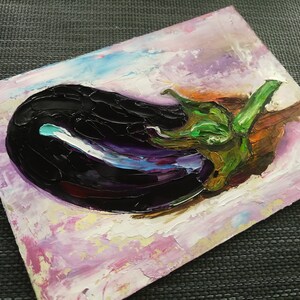 May include: An original oil painting of an eggplant. The artwork features a dark purple eggplant with green and brown accents, set against a textured background of pink, white, and blue hues. The painting is on a small, square canvas.