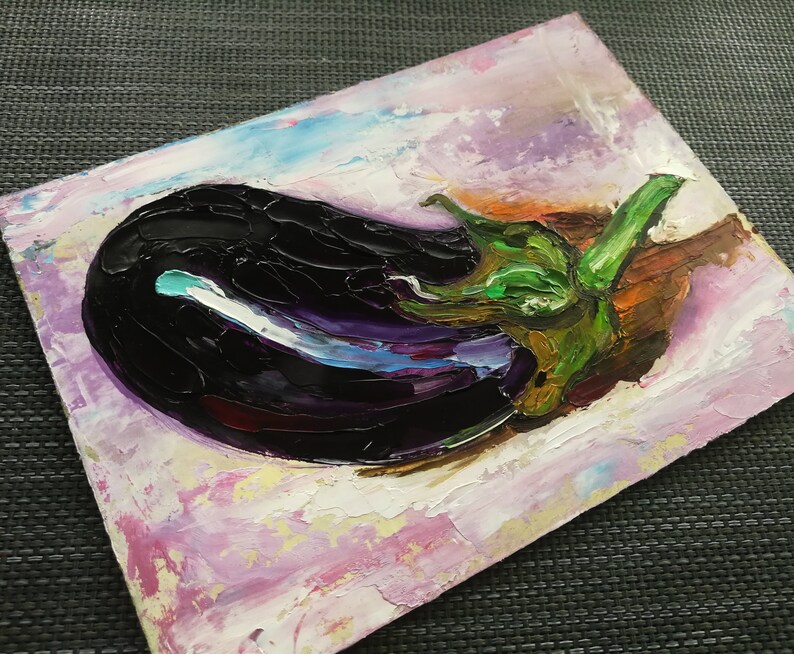 May include: An original oil painting of an eggplant. The artwork features a dark purple eggplant with green and brown accents, set against a textured background of pink, white, and blue hues. The painting is on a small, square canvas.