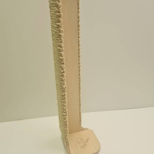 Pu&ograve; includere: Un alto tiragraffi per gatti in legno di colore naturale con corda di sisal avvolta attorno al davanti. Il palo ha una base larga con il testo "Big Paw" inciso su di essa.