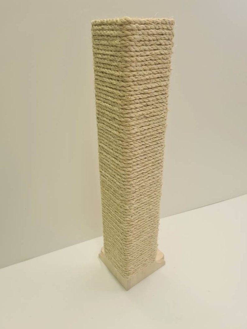 Pu&ograve; includere: Un tiragraffi per gatti alto e beige con una base quadrata avvolta in corda di sisal naturale.