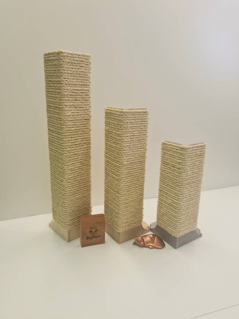 Pu&ograve; includere: Tre tiragraffi per gatti beige di diverse altezze, avvolti in corda di sisal naturale. I pali sono in legno e hanno una base quadrata. Il palo pi&ugrave; piccolo &egrave; a destra, il palo centrale &egrave; al centro e il palo pi&ugrave; alto &egrave; a sinistra. I pali sono su una superficie bianca. Il nome del marchio "BigPaw" &egrave; visibile su un piccolo blocco di legno davanti ai pali.