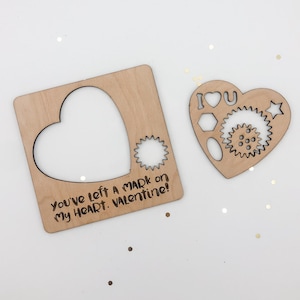 May include: Wooden Valentine's Day card with a heart-shaped cutout and the text "You've left a mark on my heart. Valentine!"
