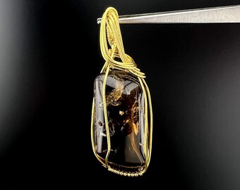 May include: A gold wire wrapped pendant featuring a dark brown, rectangular gemstone.