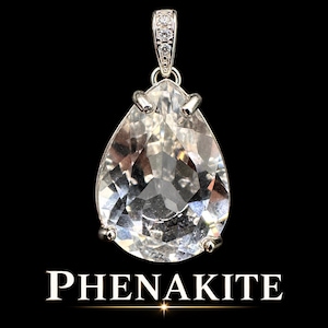 May include: A pear-shaped, faceted clear phenakite gemstone pendant set in a silver-toned metal prong setting. The bail is decorated with three small, clear, round-cut stones. The word PHENAKITE is printed in white capital letters below the pendant.