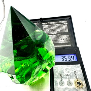 May include: A large, green, faceted glass pyramid on a digital scale. The scale reads 35.94 grams.