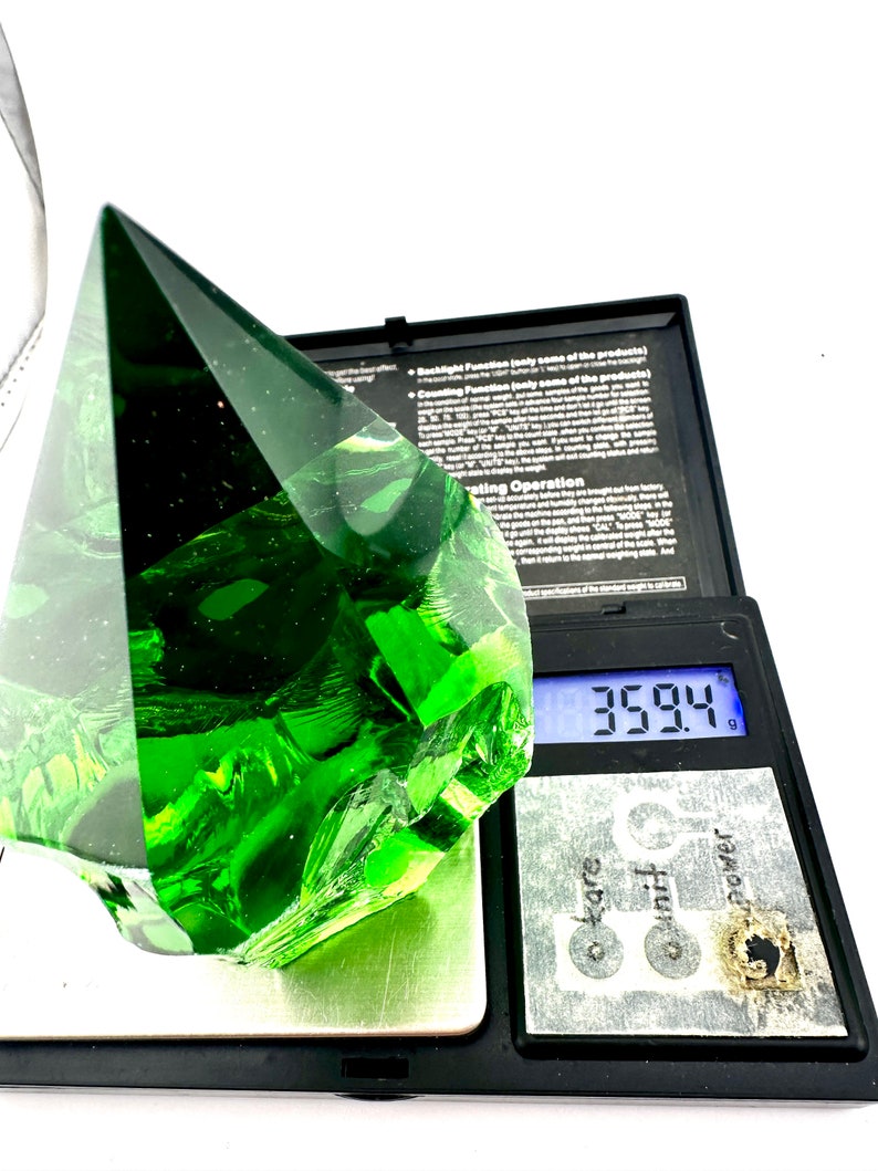 May include: A large, green, faceted glass pyramid on a digital scale. The scale reads 35.94 grams.