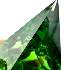 May include: A large, faceted, green crystal pyramid with a sharp point.