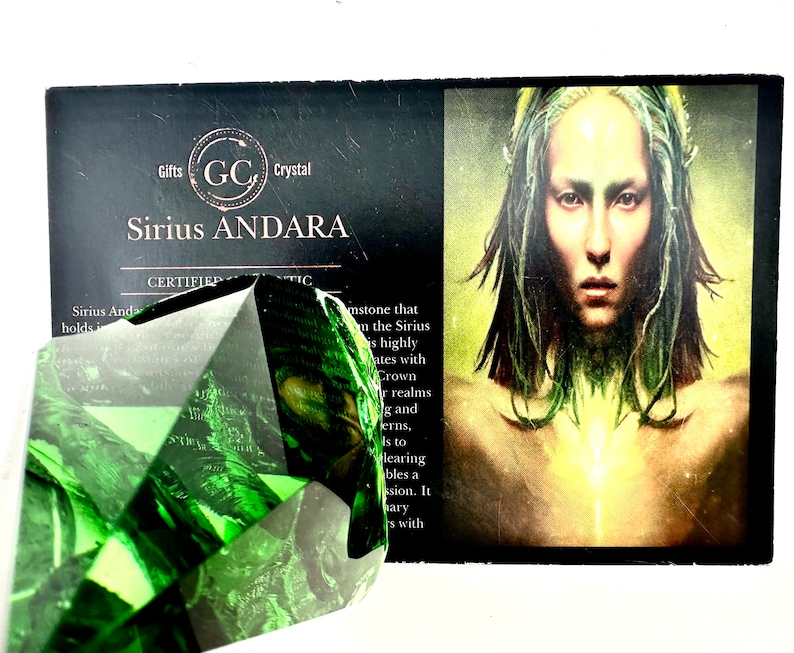 May include: A green, faceted, crystal gemstone with the text "Sirius Andara" and "Certified Authentic" on a black card with a woman's image.