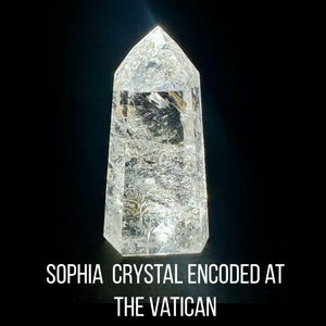 Peut inclure: Une pointe de cristal de quartz transparent à facettes avec des fractures et des inclusions internes. Le texte sous le cristal indique : SOPHIA CRYSTAL ENCODED AT THE VATICAN. L'objet est placé sur un fond noir uni, soulignant sa transparence.