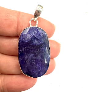 May include: A silver pendant with a large, oval-shaped purple gemstone. The gemstone has a swirling, marbled pattern.