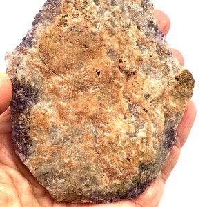 May include: A large, flat, irregularly shaped amethyst crystal with a purple hue and brown and white inclusions. The crystal is about 6 inches in diameter.