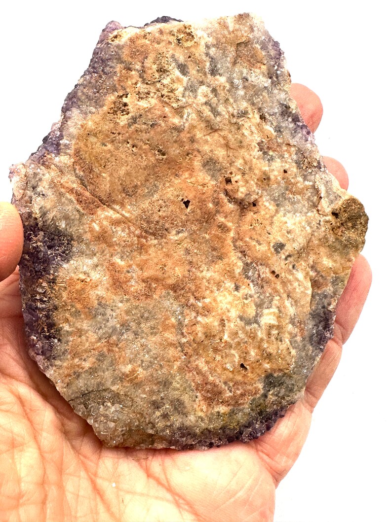 May include: A large, flat, irregularly shaped amethyst crystal with a purple hue and brown and white inclusions. The crystal is about 6 inches in diameter.