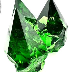 May include: Three large, faceted, green glass crystals. The crystals are clear and have a slight swirl pattern.