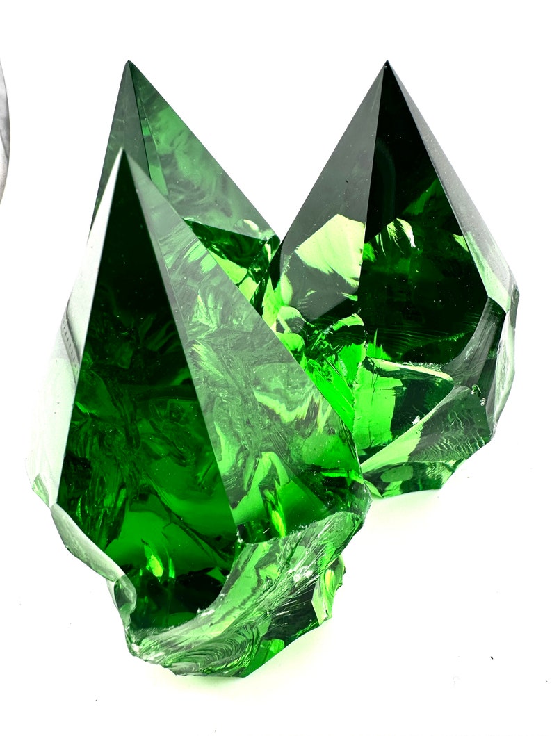 May include: Three large, faceted, green glass crystals. The crystals are clear and have a slight swirl pattern.