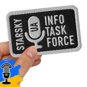 Może przedstawiać: Haftowana naszywka z napisem "STARKY INFO TASK FORCE" i grafiką mikrofonu. Naszywka jest czarna z białymi i szarymi akcentami. Naszywka jest prostokątna z zaokrąglonymi rogami.