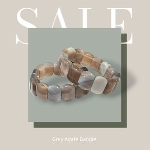 May include: Two grey agate stone bracelets stacked on top of each other. The bracelets are made of smooth, rounded stones with a light grey and white pattern. Grey Agate Bangle.