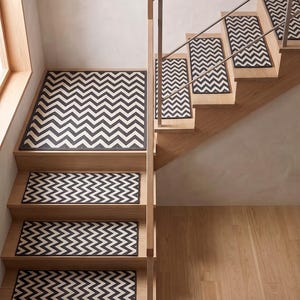 Op de afbeelding: Een set rechthoekige traptredenmatten met een herhalend zwart-wit chevronpatroon. Elke mat is ontworpen om het horizontale oppervlak van een houten trede te bedekken, wat zorgt voor een consistent geometrisch ontwerp op de trap.