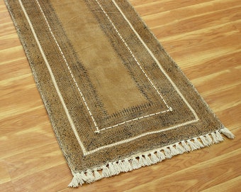 May include: A brown runner rug with a black and white geometric pattern and fringe on the ends.