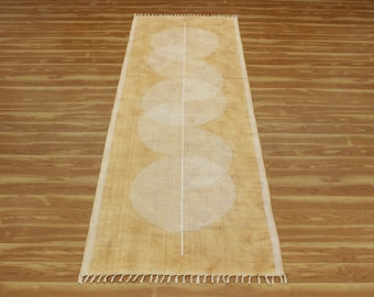 Op de afbeelding: Een beige loper met een wit geometrisch patroon van overlappende cirkels. De loper heeft een franje rand.