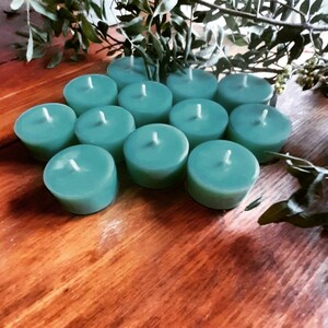 May include: A group of teal tealight candles arranged in a circular pattern on a wooden surface.