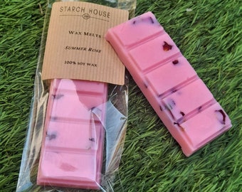 May include: Two pink wax melts with dried rose petals, packaged in a clear plastic bag. The label reads "Starch House Wax Melts Summer Rose 100% Soy Wax".