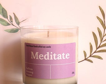 May include: A clear glass jar candle with a purple label that reads "Meditate" and "Starch House Handcrafted soy candle". The label also lists the scent notes: Saffron, Nutmeg, Pepper. The candle is 220g.