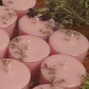 May include: A group of pink tea light candles with dried lavender flowers embedded in the wax. The candles are arranged in a circle.