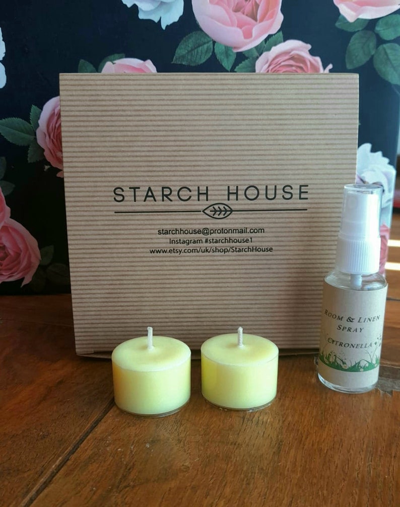 May include: A brown cardboard box with the text "STARCH HOUSE" printed on it. The box is next to two yellow tea light candles and a small bottle of room and linen spray labeled "Citronella".