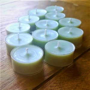 May include: A group of teal tealight candles arranged in a triangular pattern on a wooden surface.