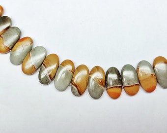 Puede incluir: Una hebra de cuentas de piedras preciosas ovaladas con una mezcla de colores marrón, naranja y gris. Las cuentas están enhebradas en un alambre.