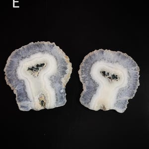 May include: Two agate slices with a white center and a purple outer edge. The agate slices have a unique, natural pattern.