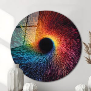 May include: A large, round wall art piece with a vibrant, swirling design. The artwork features a central black void surrounded by a burst of colorful lines in shades of red, orange, yellow, blue, and purple. The piece is displayed above a wooden cabinet.