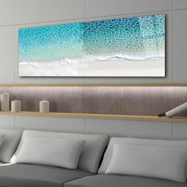 May include: A rectangular wall art piece featuring an aerial view of a turquoise ocean shoreline. The image displays clear blue water with white foam patterns washing onto a smooth, light-colored sandy beach, creating a calm coastal scene.