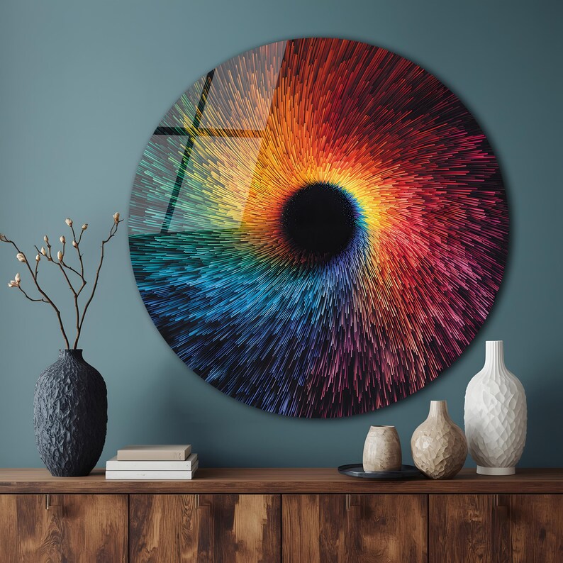May include: A large, round wall art piece with a vibrant, swirling design. The artwork features a central black void surrounded by a spectrum of colors, including red, orange, yellow, blue, and purple. The piece is mounted on a teal wall.