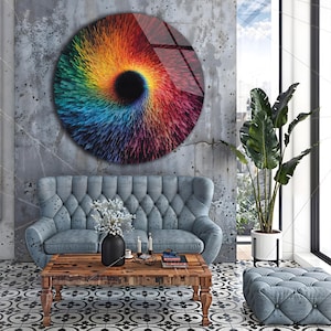 May include: A large, round wall art piece with a vibrant, swirling design in shades of red, orange, yellow, green, blue, and purple. The artwork has a black center and is mounted on a textured gray wall. The room features a blue sofa, wooden coffee table, and patterned floor.