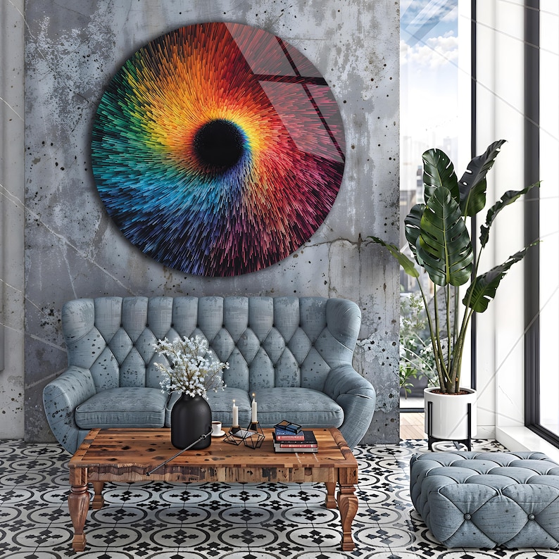 May include: A large, round wall art piece with a vibrant, swirling design in shades of red, orange, yellow, green, blue, and purple. The artwork has a black center and is mounted on a textured gray wall. The room features a blue sofa, wooden coffee table, and patterned floor.