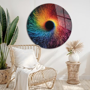 May include: A round wall art piece with a vibrant, swirling design. The artwork features a central black vortex surrounded by a spectrum of colors, including red, orange, yellow, green, and blue. The piece is mounted on a white wall, adding a modern touch to the room.
