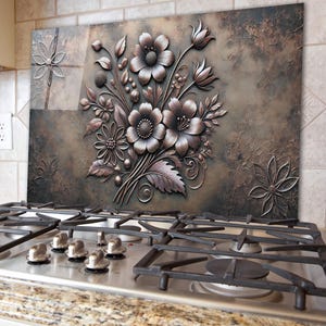 Peut inclure: Une crédence en métal décorative avec un motif floral 3D. Les fleurs sont dans des tons de brun et d'or et ont un aspect texturé et gaufré. L'arrière-plan est brun foncé avec une finition vieillie.