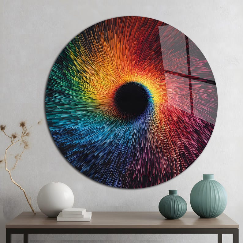 May include: A round wall art piece with a vibrant, swirling design. The artwork features a central black void surrounded by a spectrum of colors, including red, orange, yellow, green, and blue. The piece is displayed on a wall above a wooden table.