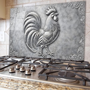 Puede incluir: Un gallo plateado con un diseño detallado se presenta sobre un fondo texturizado gris y blanco. El gallo está de pie sobre una superficie decorativa con adornos de desplazamiento.