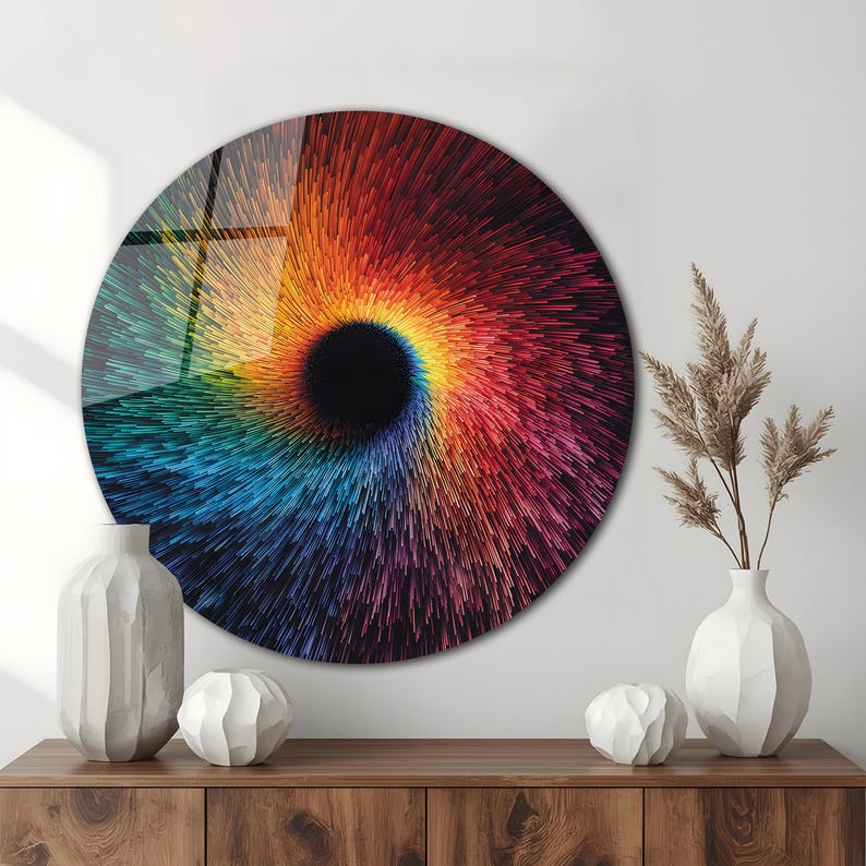 May include: A large, round wall art piece with a vibrant, swirling design. The artwork features a central black void surrounded by a burst of colorful lines in shades of red, orange, yellow, blue, and purple. The piece is displayed above a wooden cabinet.