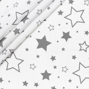 Peut inclure: Tissu blanc avec un motif répétitif d'étoiles grises de différentes tailles. Certaines étoiles sont pleines, d'autres sont en contour. Le tissu est plié, créant des lignes diagonales.