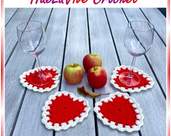May include: Red and white crochet heart-shaped coasters with wine glasses and apples on a wooden table. The coasters have a scalloped white border. The text "HueLaVive Crochet" is at the top of the image.